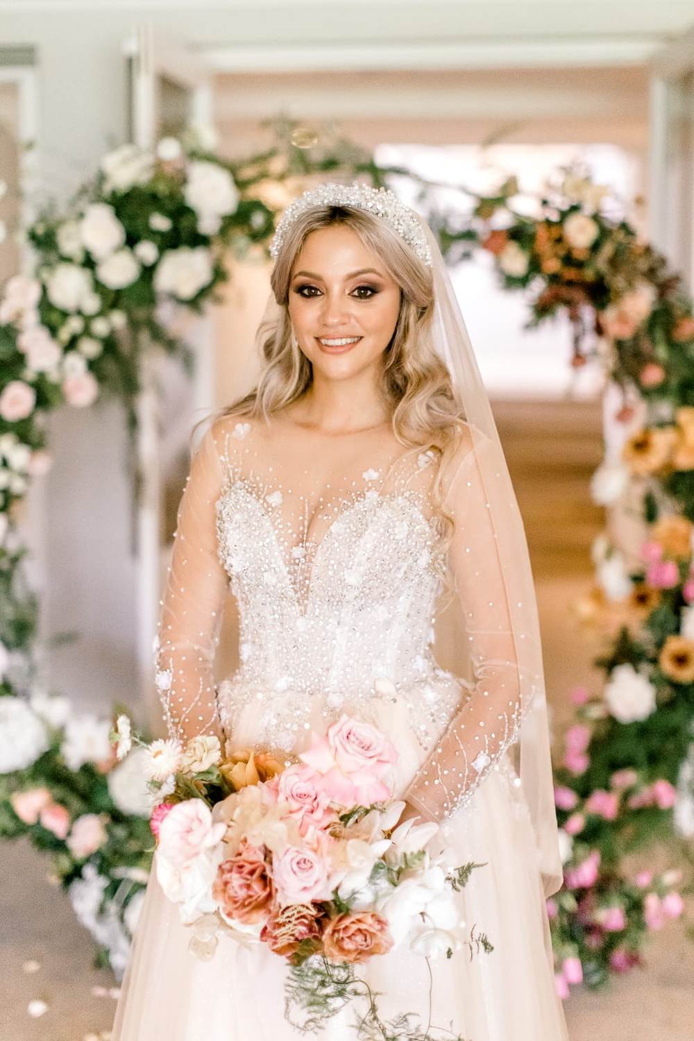 Bride beneath a floral arch in an illusion lace Saarahjasmin Couture gown